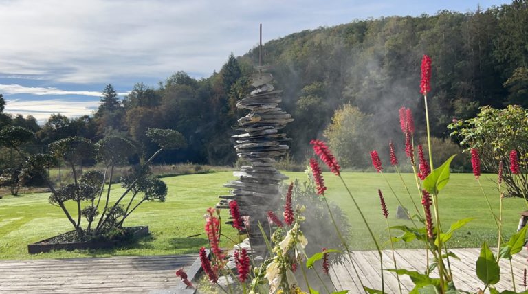 Aménagement de jardin artistique avec sculpture en pierre et terrasse en bois et brume